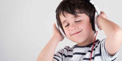 Kind hört englische Lieder und Geschichten beim Spielen zu Hause